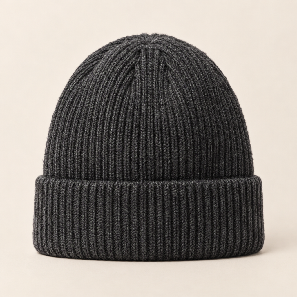 Front view of the charcoal-gray Frostline Knit Beanie with ribbed knit and folded cuff on a warm neutral background.